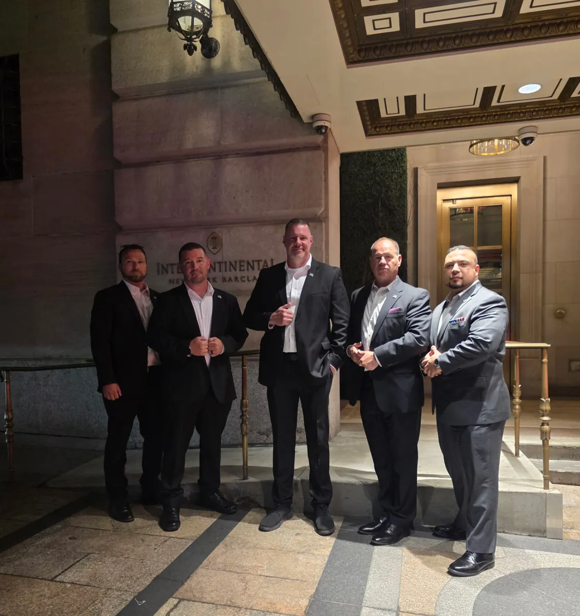 James Gonzales, owner of Shadow Securities, with his executive protection team in suits outside the InterContinental New York Barclay hotel in Midtown Manhattan at night.