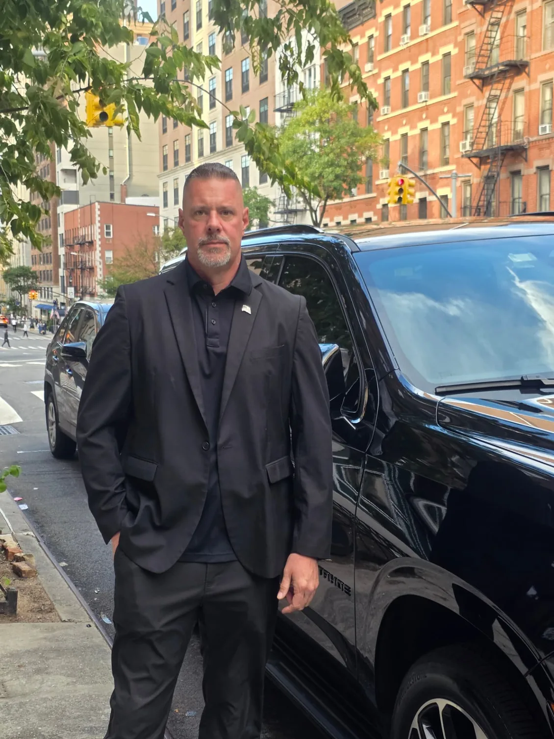 Protection agent standing post beside a black SUV during a residential stop