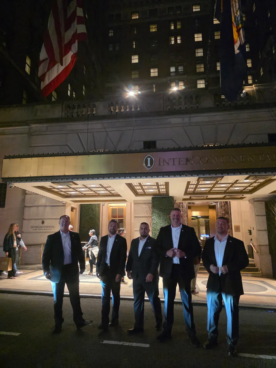 Shadow Securities executive protection agents in suits providing arrival security outside the InterContinental New York Barclay hotel in Midtown Manhattan at night.