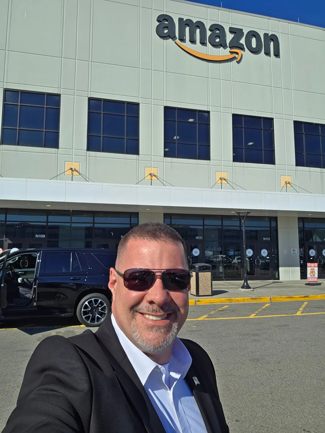 Shadow Securities armed security officer beside a black SUV outside an Amazon distribution facility in New York