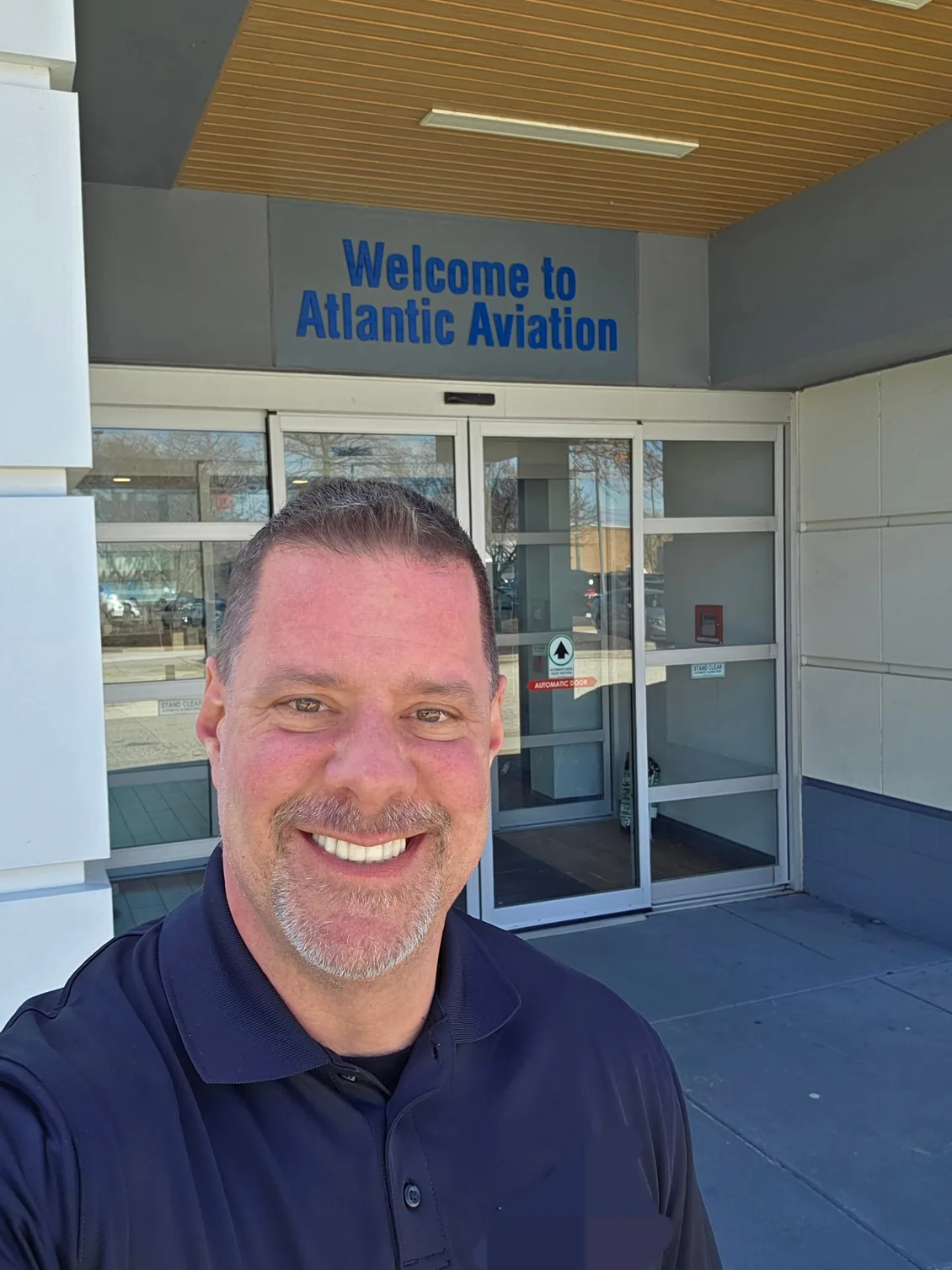 Shadow Securities armed security officer standing outside the entrance of an Atlantic Aviation FBO terminal