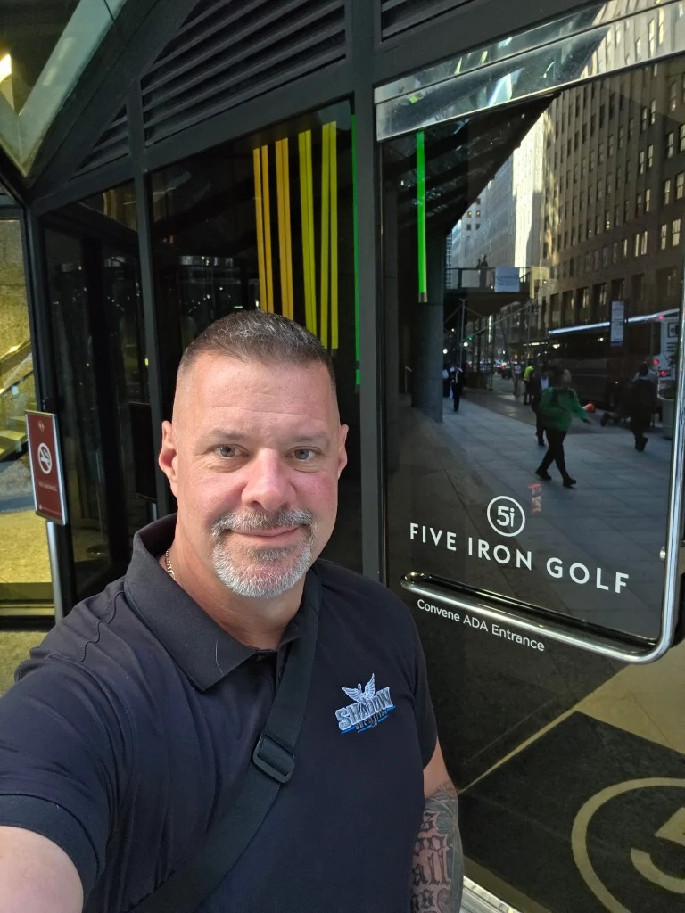 James Gonzales of Shadow Securities in a branded polo at the ADA entrance of Five Iron Golf in New York