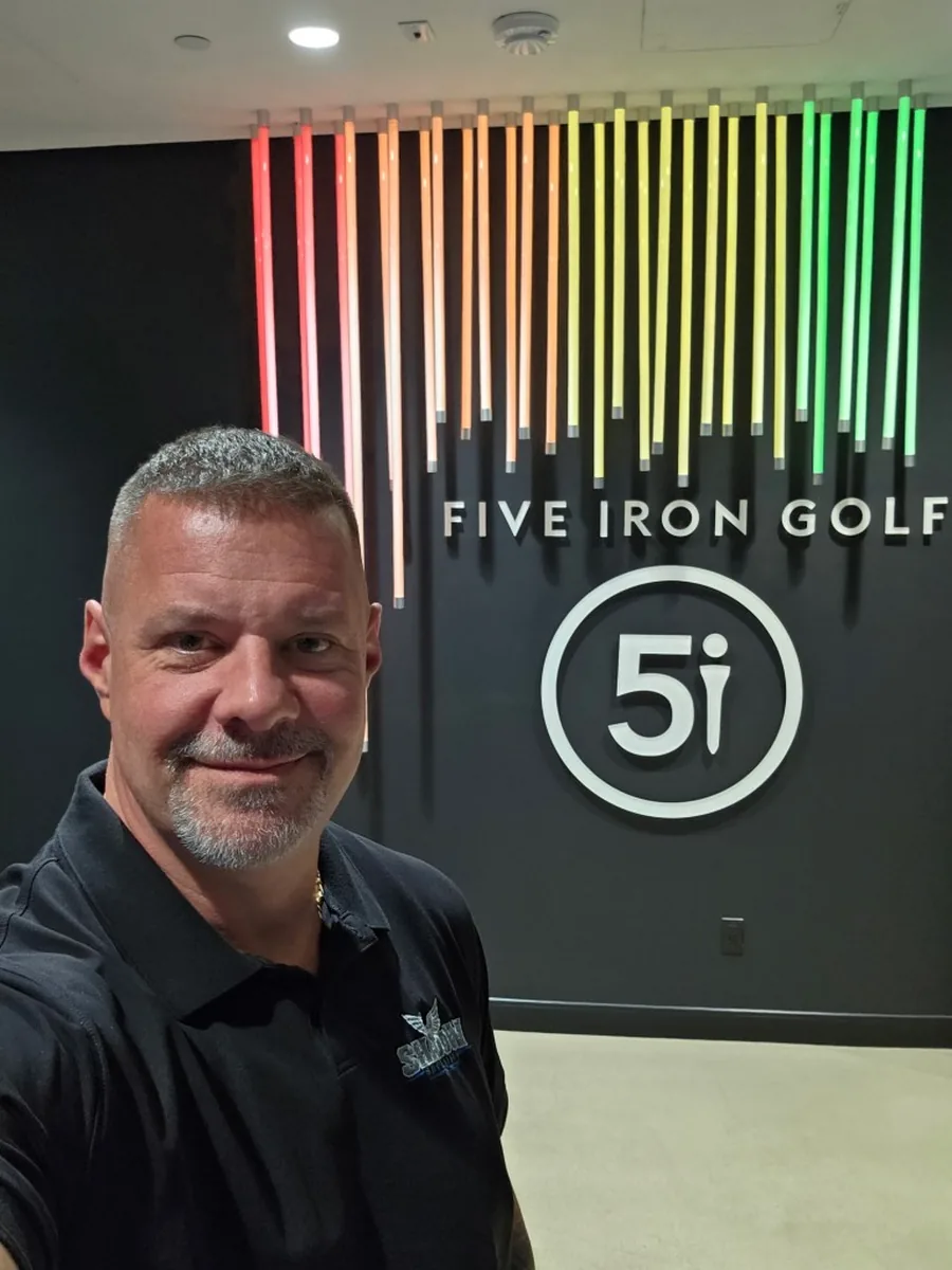James Gonzales of Shadow Securities in a branded polo in the lobby of Five Iron Golf in New York